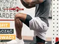 Mężczyzna w stroju sportowym wykonuje ćwiczenie w siłowni CrossFit.